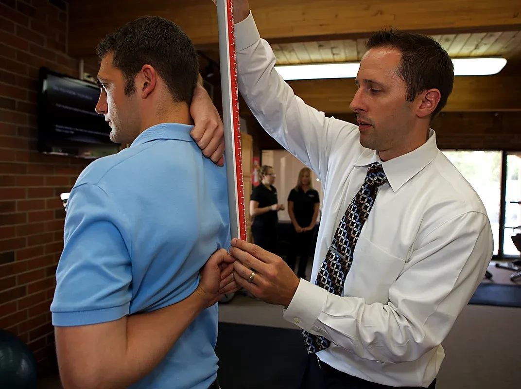 A ChiroFit doctor measuring a patient's posture during a first-visit examination